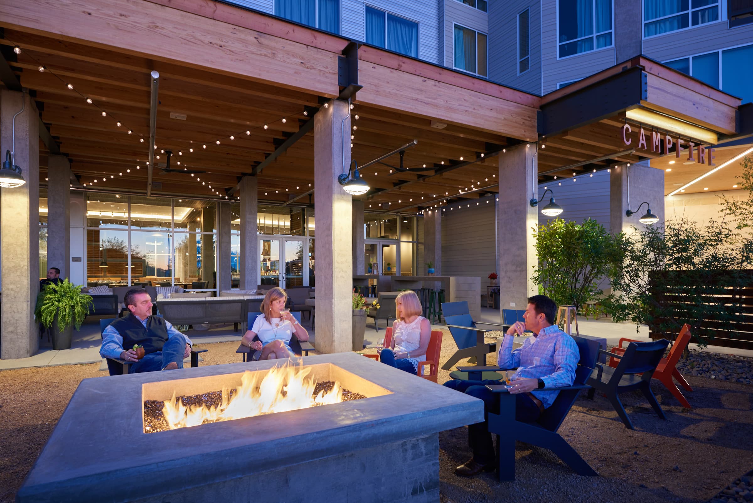 People gathered at a campfire in The Stella Hotel in Bryan, Texas
