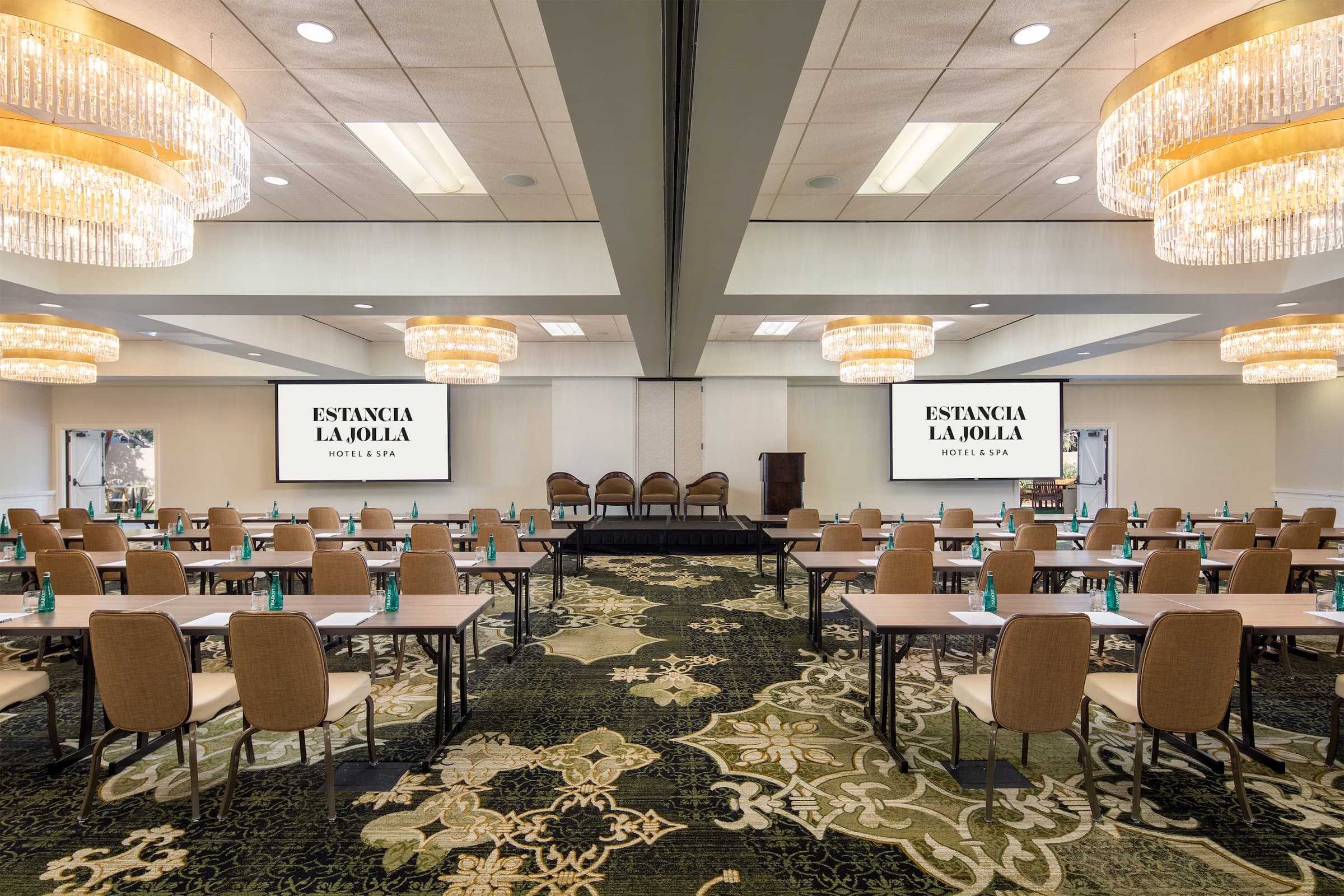 Meeting space fitted with multiple tables, stage and chandeliers at Estancia La Jolla, California
