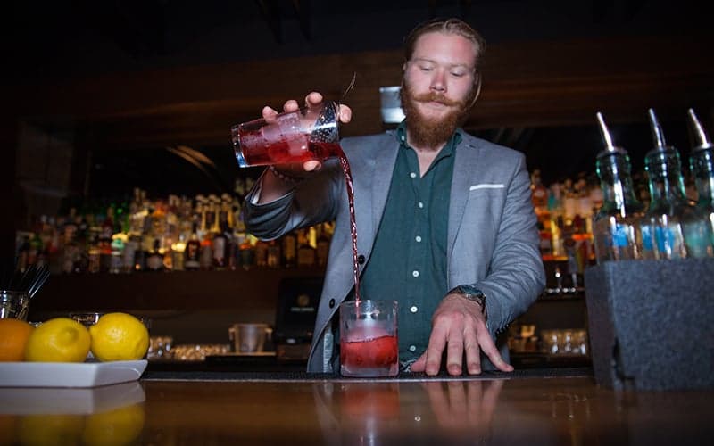 Bartender pouring a cocktail at The Rose, a craft cocktail lounge