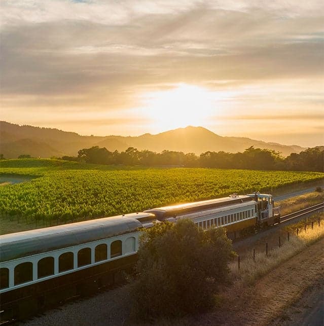 The Napa Valley Wine Train on the tracks next to the fields during sunrise