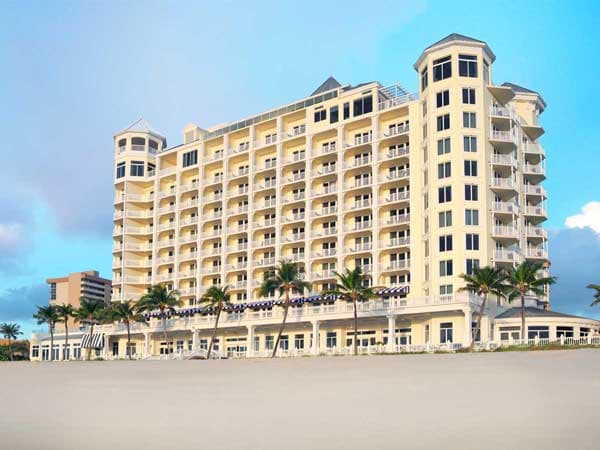 Exterior of the beautiful Pelican Gran Beach resort, surrounded by palm trees and a gorgeous beach front