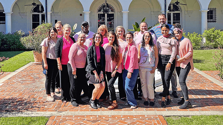 Group of employees huddled together wearing pink