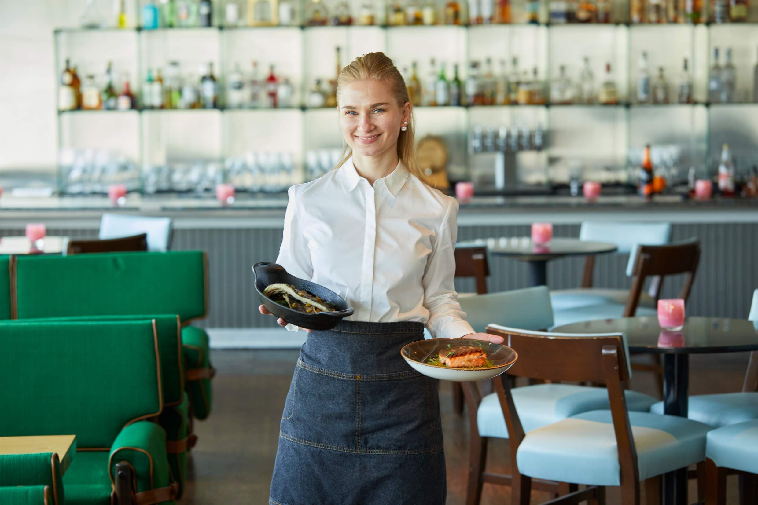 A Noble House waiter delivering food in a restaurant.