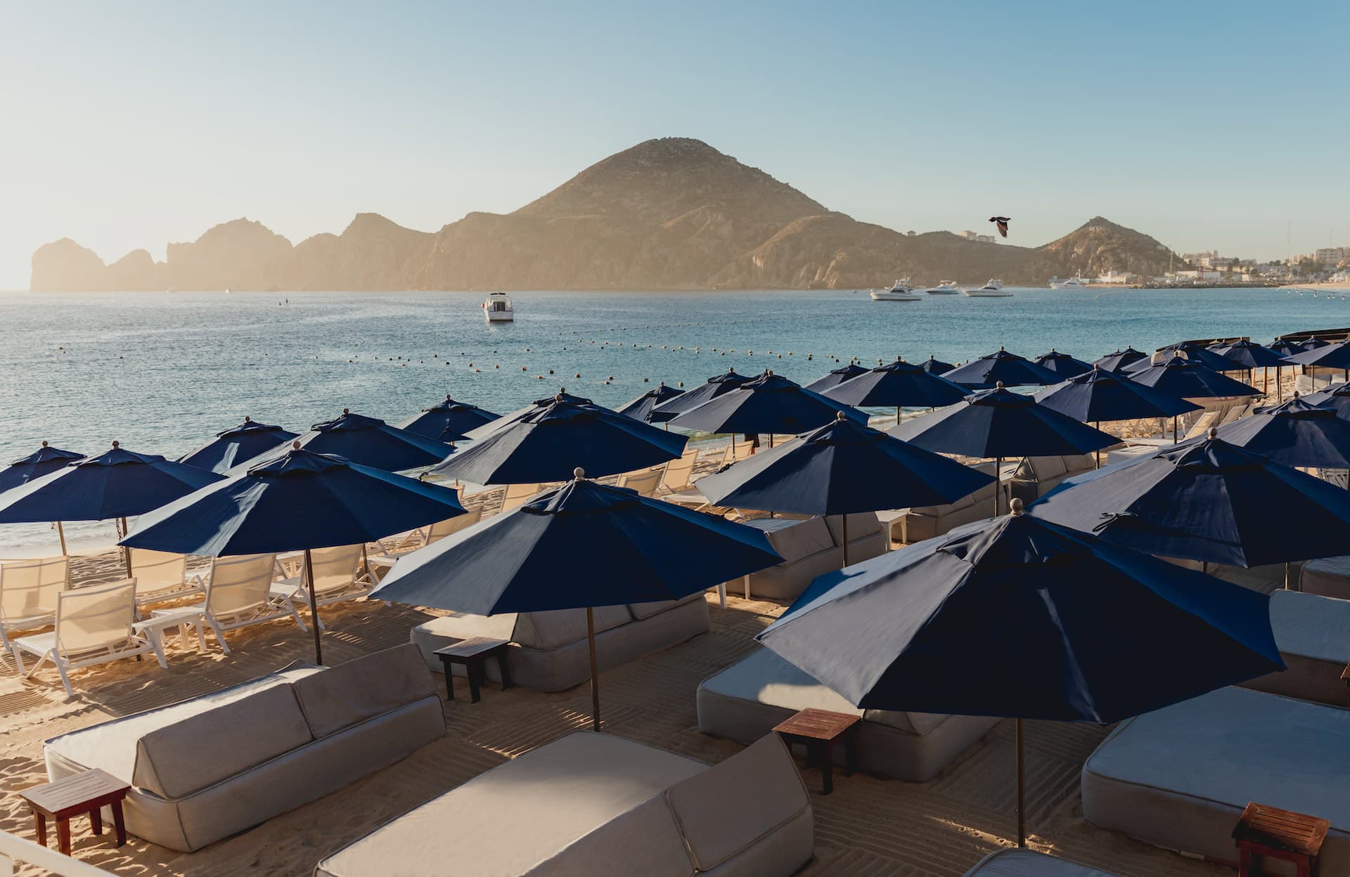 Lounge chairs and couches with sunshades at a Noble House Hotels & Resorts property